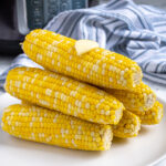 Pinterest Pin with text 'Pressure Cooker Corn on the Cob', image of a stack of cooked corn on a plate.