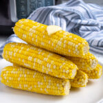 Pinterest Pin with text 'Pressure Cooker Corn on the Cob', image of a stack of cooked corn on a plate.