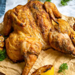 Pinterest Pin with text 'How to Spatchcock a Whole Chicken (And How to Grill It', image of golden brown grilled chicken on a cutting board.