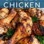 Pinterest Pin with text 'Greek Marinated Grilled Chicken', image of a plate piled high with golden brown grilled chicken legs.