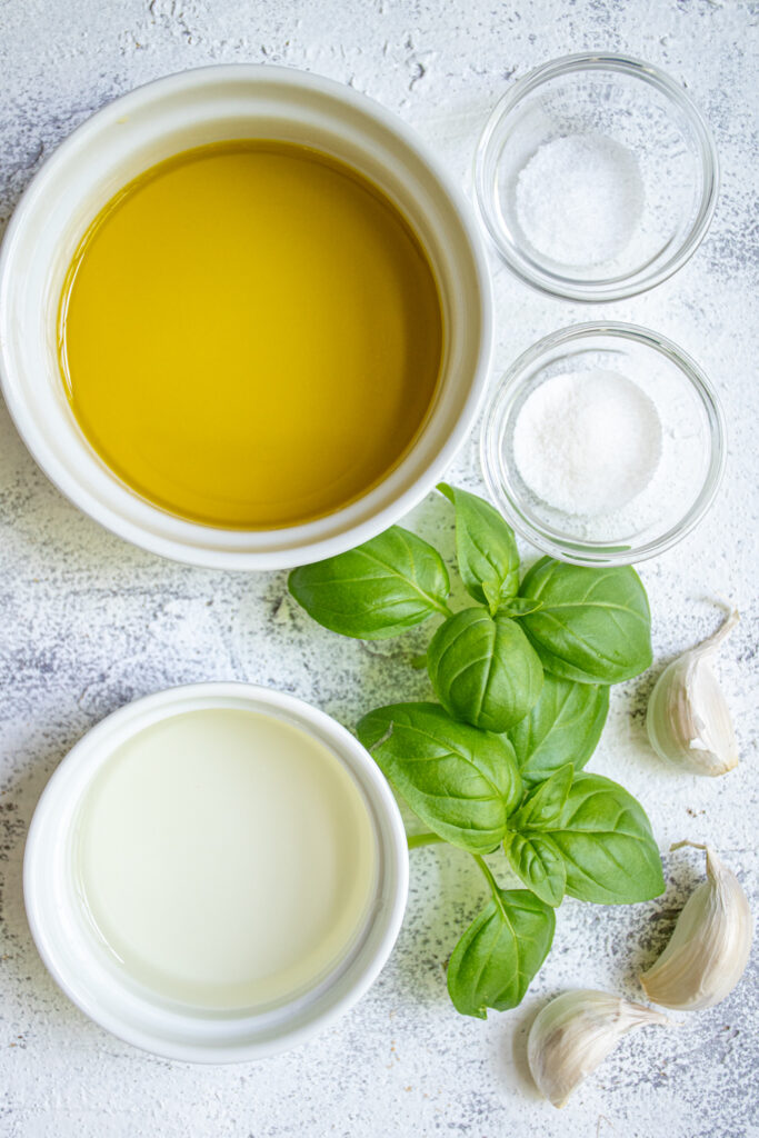 Ingredients needed to make a marinade for grilled vegetables including olive oil, garlic, and fresh basil.