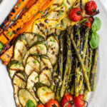 Pinterest pin with text 'The Best Grilled Vegetable Marinade', image of a platter filled with freshly grilled veggies laid out nicely on a platter.