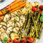 Pinterest pin with text 'Marinated Grilled Vegetables', image of a platter filled with freshly grilled veggies laid out nicely on a platter.