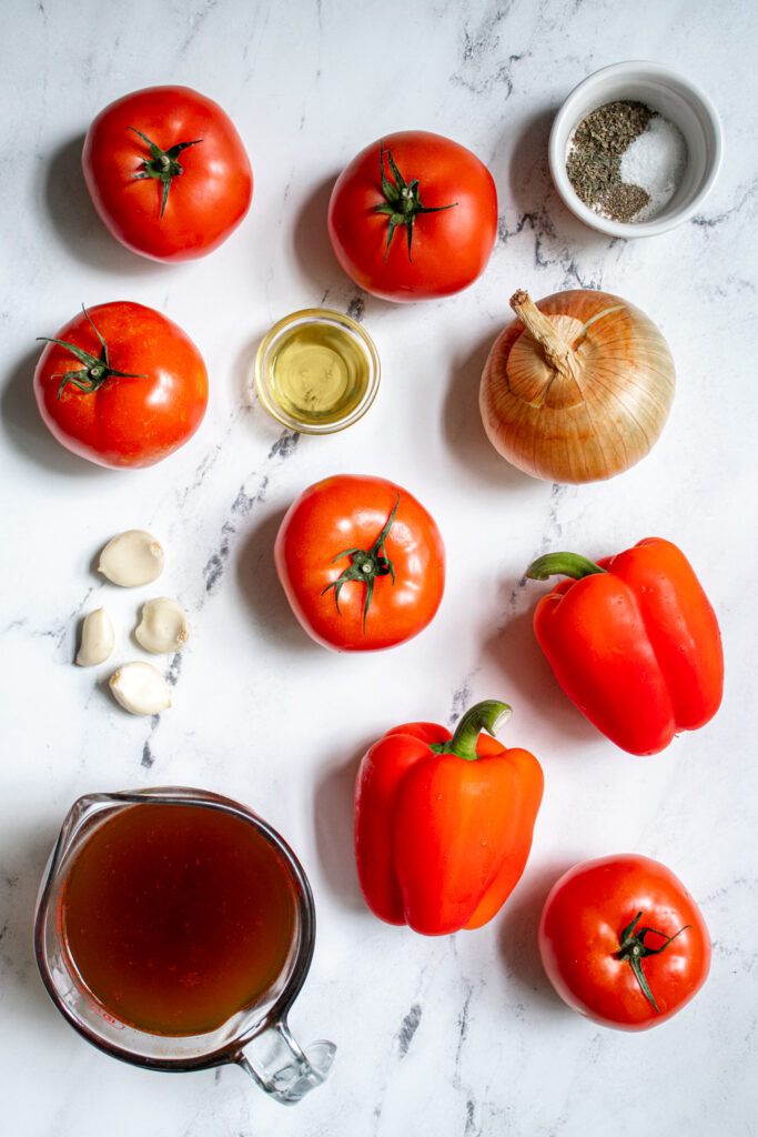 All the ingredients needed to make roasted red pepper and tomato soup laying flat on a countertop.