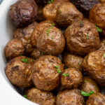 Pinterest pin with text 'Air Fryer Baby Potatoes', image showing a white serving dish filled with salty baby potatoes.