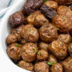 Pinterest pin with text 'Air Fryer Baby Potatoes', image showing a white serving dish filled with salty baby potatoes.