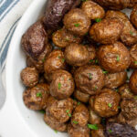Pinterest pin with text 'Air Fryer Baby Potatoes', image showing a white serving dish filled with salty baby potatoes.
