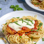 Pinterest Pin with text 'Oven Baked Chicken Parmesan' image of a plate filled with spaghetti topped with a chicken parm.