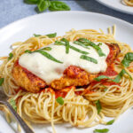 Pinterest Pin with text 'Oven Baked Chicken Parmesan' image of a plate filled with spaghetti topped with a chicken parm.