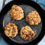 Pinterest Pin with text 'Mediterranean Turkey Burgers' image of a black skillet with four just cooked turkey burgers.