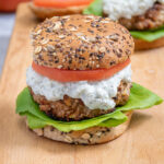 Pinterest Pin with text 'Mediterranean Turkey Burgers' image of a greek turkey burger with Tzatziki sauce on a butcher block.