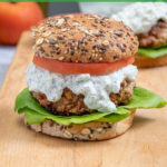 Pinterest Pin with text 'Mediterranean Turkey Burgers' image of a greek turkey burger with Tzatziki sauce on a butcher block.