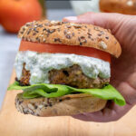 Pinterest Pin with text 'Mediterranean Turkey Burgers' image of a greek turkey burger with Tzatziki sauce on a butcher block.
