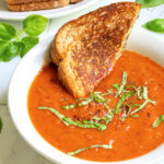 Pinterest Pin with text 'Roasted Red Pepper & Tomato Soup, easy and healthy, made with fresh veggies' image showing a white bowl of tomato soup with a slice of grilled cheese.