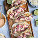 Pinterest Pin with text overlay 'Tuna Steak Tacos' images of a tray full of seared tuna tacos with garnishes.