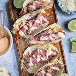 Pinterest Pin with text overlay 'Tuna Steak Tacos' images of a tray full of seared tuna tacos with garnishes.