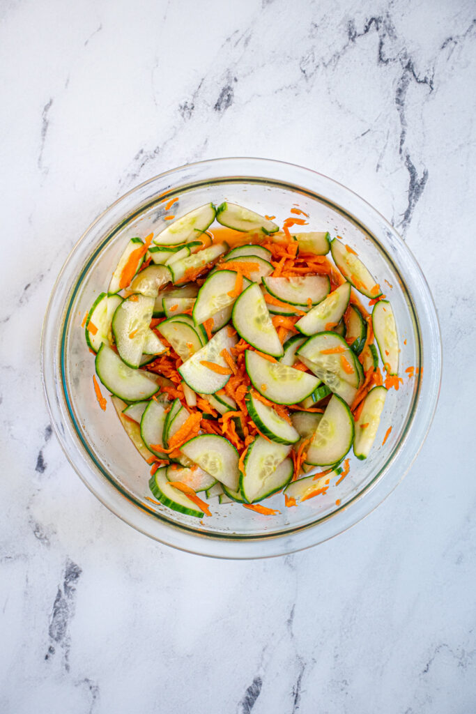 A bowl containing the quick picked veggies, carrots and cucumbers in rice vinegar.