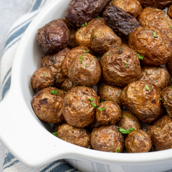 Freshly made baby potatoes in the air fryer in a white ceramic bowl.