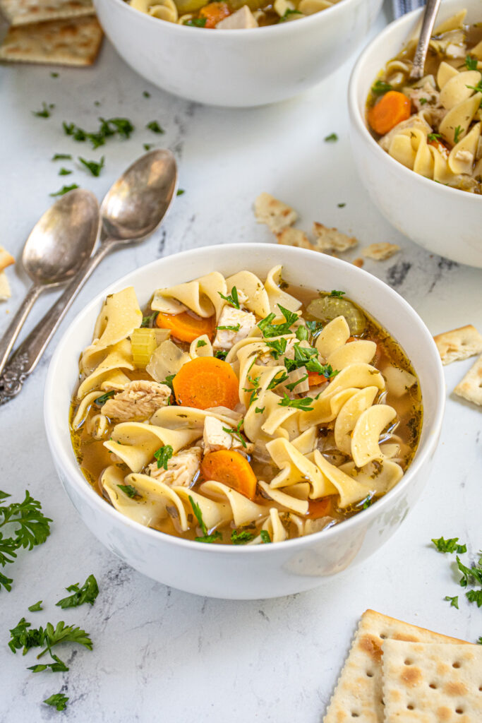 Overhead view of a bowl of easy chicken noodle soup showing off egg noodles, chunks of chicken, and fresh vegetables.