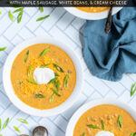 Pinterest Pin with text 'Crockpot Creamy Pumpkin Chili', image of bowls of yellow pumpkin chili topped with green onions, and sour cream.