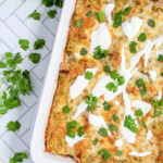 Pinterest Pin with text 'Green Chicken Enchiladas', image of white baking dish filled with green enchiladas.