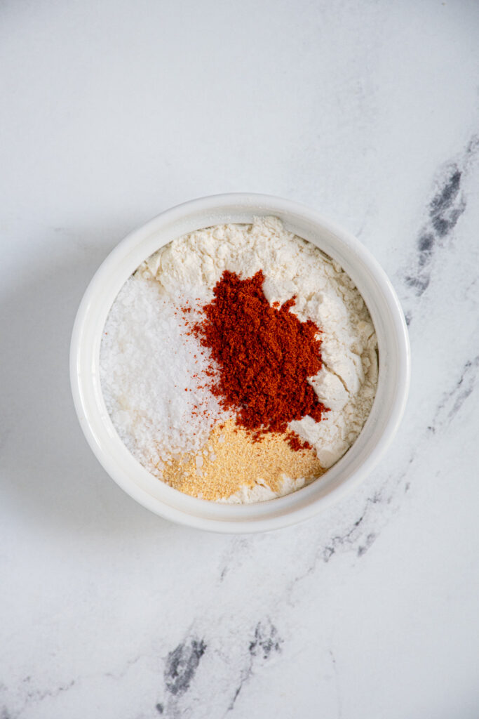 Small white bowl with flour, salt, garlic powder, and paprika.