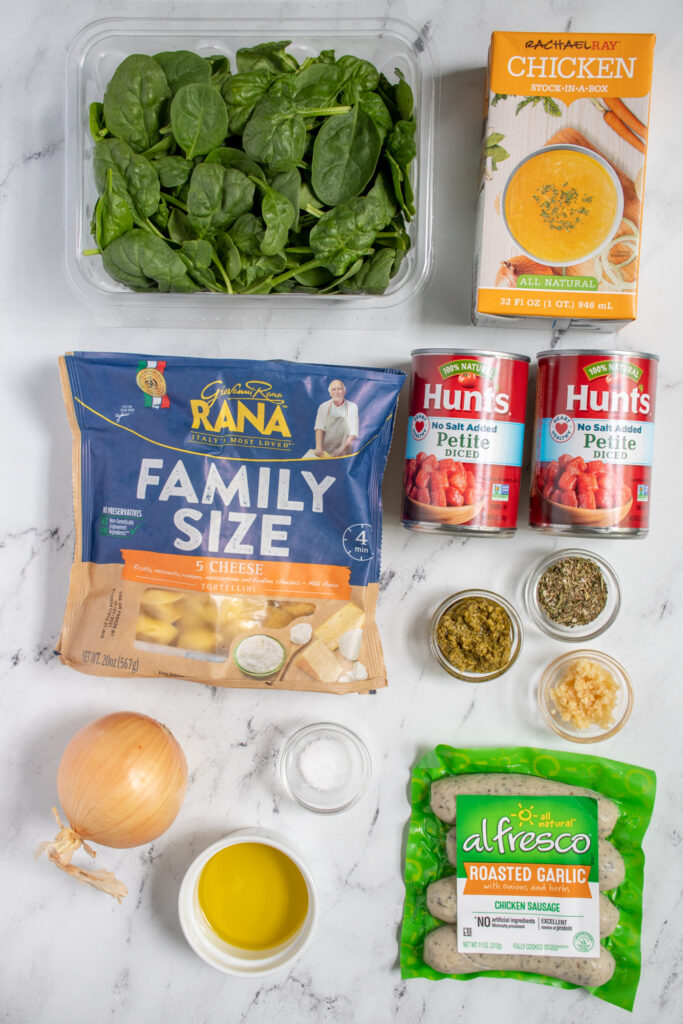 Ingredients needed to make tortellini soup laid out of a countertop.