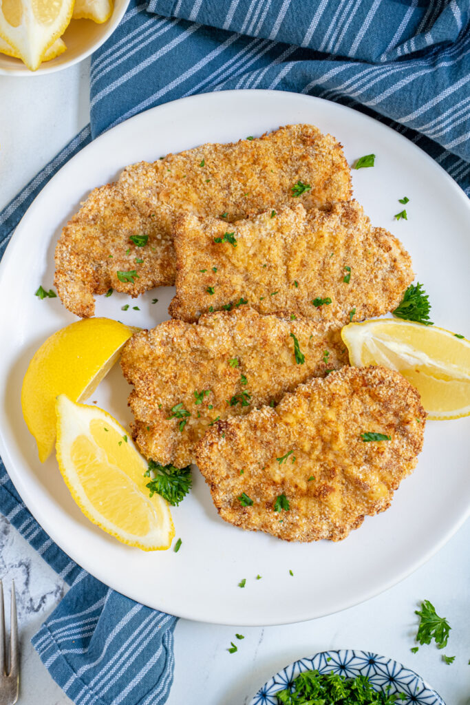 Overhead view of close up of air fryer pork schnitzel showing off golden brown breading and garnished with fresh parsley.