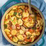 Pinterest Pin with text "Tortellini Soup with Chicken Sausage", image of a pot of tortellini soup.