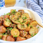 Pinterest Pin with text 'Warm German Potato Salad', image of a white bowl filled with German potato salad with bacon and fresh parsley.