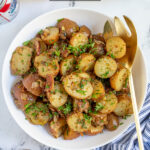 Pinterest Pin with text 'Warm German Potato Salad', image of a white bowl filled with German potato salad with bacon and fresh parsley.