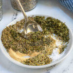 Pinterest Pin with text 'Homemade Italian Seasoning',image of a small plate with Italian seasoning ingredients.