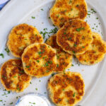 Pinterest Pin with text 'Leftover Mashed Potato Cakes', image showing golden brown leftover mashed potato cakes on a platter with fresh parsley.