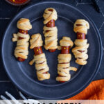 Pinterest Pin with text 'Halloween Mummy Dogs', image of mummy dogs with mustard eyes on a black plate.