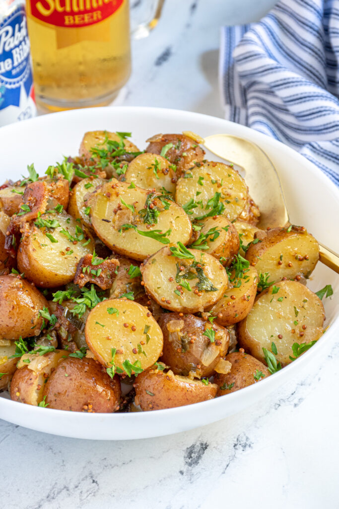 close up of a bowl of German potato salad covered with bacon bits and fresh parsley.