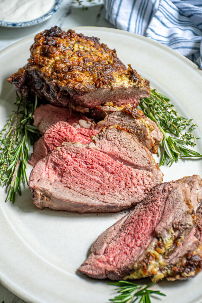 Close up of a slice of boneless leg of lamb with a pink center and crispy looking top.