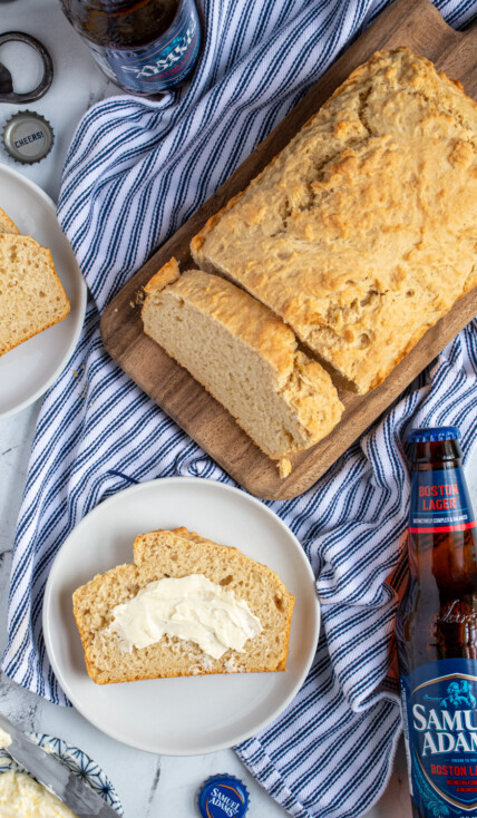 Overhead view of a loaf of easy beer bread with a slice on a plate slathered in butter.