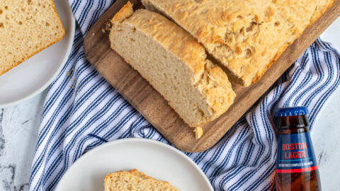 Overhead view of a loaf of easy beer bread with a slice on a plate slathered in butter.