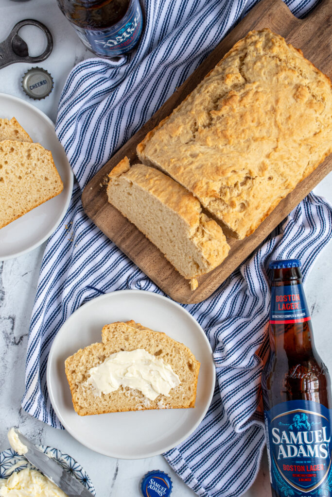 Overhead view of a loaf of easy beer bread with a slice on a plate slathered in butter.