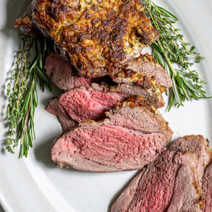 Overhead close up of a half sliced up roasted leg of lamb show tender pink meat.