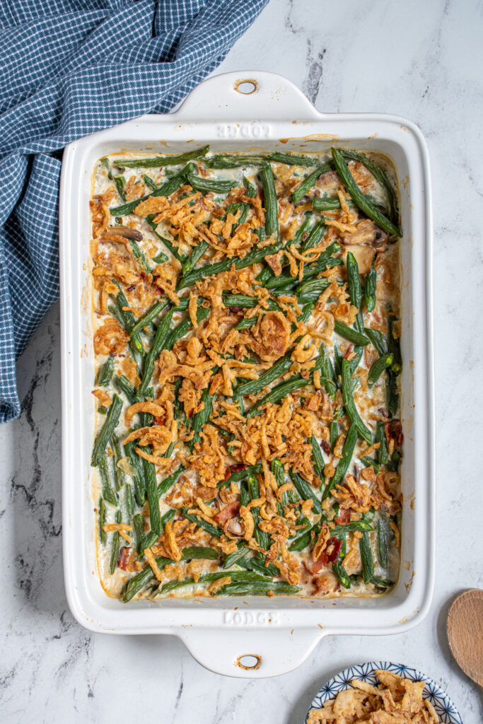 Overhead of a casserole dish with homemade green bean casserole with bacon topped with golden brown crispy fried onions.
