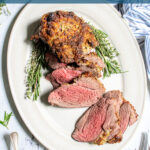 Pinterest Pin with text 'Roasted Boneless Leg of Lamb', image of roasted lamb on a platter with slices showing off a pink tender center.