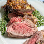Pinterest Pin with text 'Roasted Boneless Leg of Lamb', image of roasted lamb on a platter with slices showing off a pink tender center.