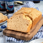 Pinterest Pin with text 'Beer Bread', image of a slice of easy beer bread leaning on a loaf on a cutting board.