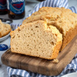 Pinterest Pin with text 'Beer Bread', image of a slice of easy beer bread leaning on a loaf on a cutting board.