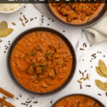 Pinterest Pin with text 'Leftover Lamb Curry', image of three black bowls filled with curry garnished with parsley.