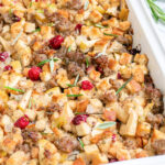 Pinterest Pin with text 'Sausage Cranberry Apple Stuffing',image of a white casserole dish full of stuffing.