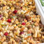 Pinterest Pin with text 'Sausage Cranberry Apple Stuffing',image of a white casserole dish full of stuffing.