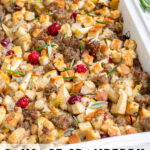 Pinterest Pin with text 'Sausage Cranberry Apple Stuffing',image of a white casserole dish full of stuffing.