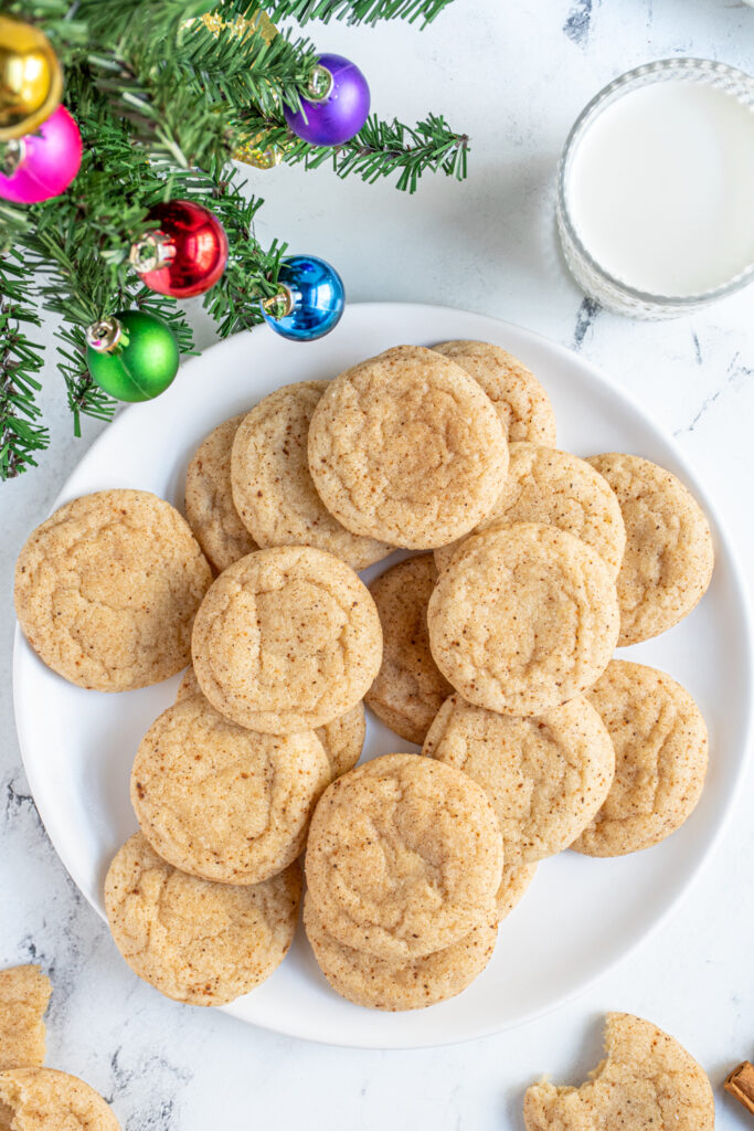 A white plate filled with eggnog snickerdoodles with suagrary outside with cinnamon and nutmeg.